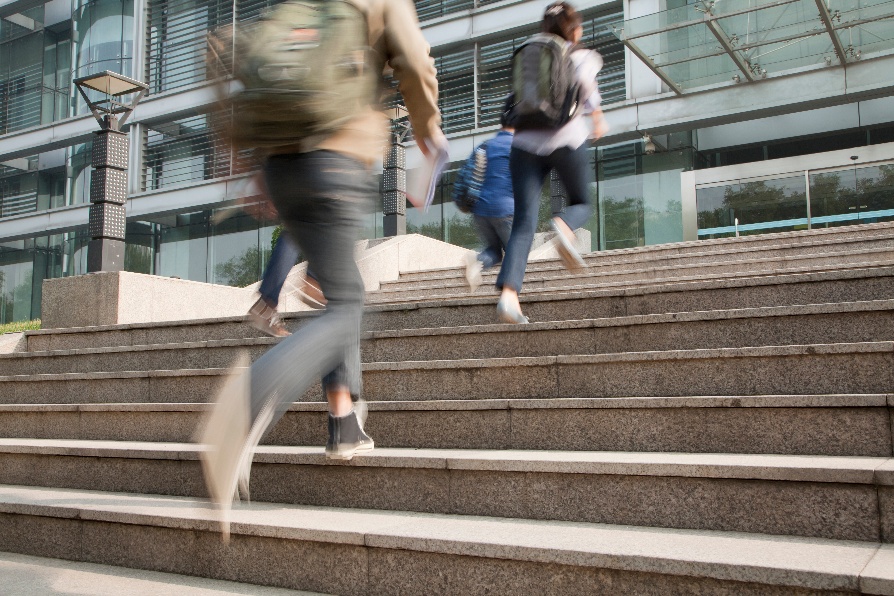 Students running up stairs with backpacks